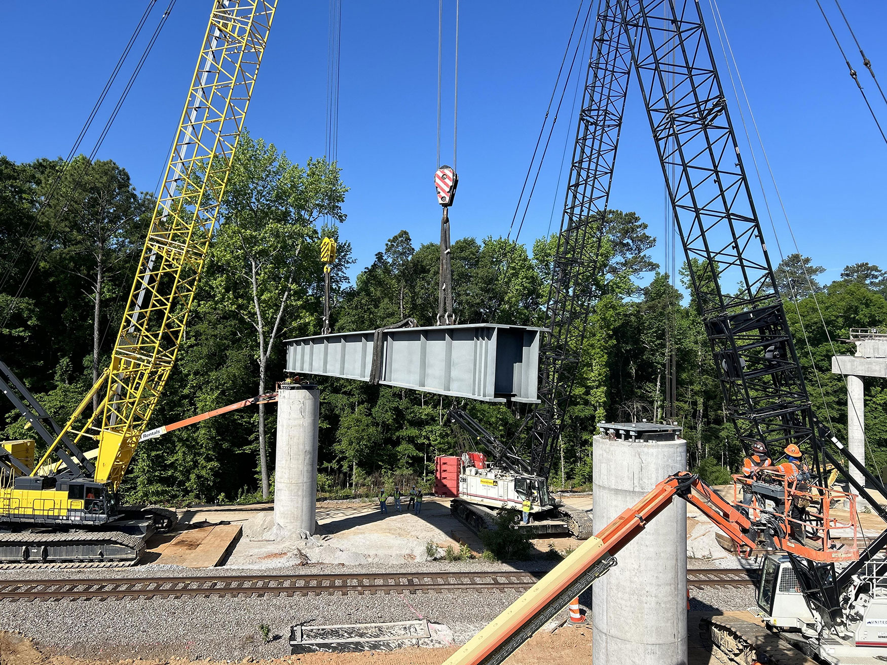 Two cranes lifting a 170,000 lbs. (85 tons) steel beam used to support girders over the CSX Railroad line.